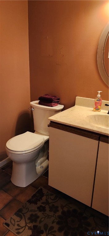 Vanity with an integrated sink and neutral-toned countertop, paired with a standard-profile toilet and tile flooring
