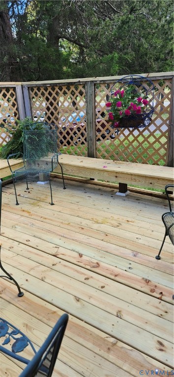 Exterior wood deck featuring built-in bench seating and decorative lattice privacy screening