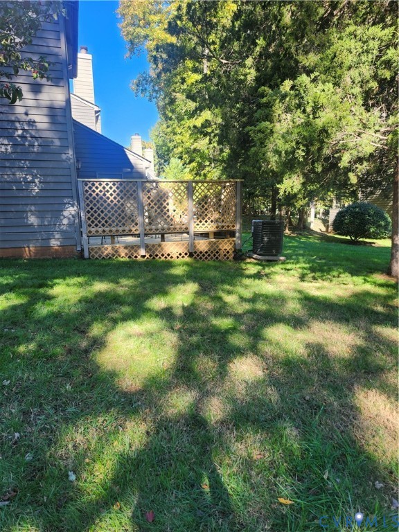 Exterior rear wood deck featuring lattice privacy screening, siding, and an expansive lawn with mature trees