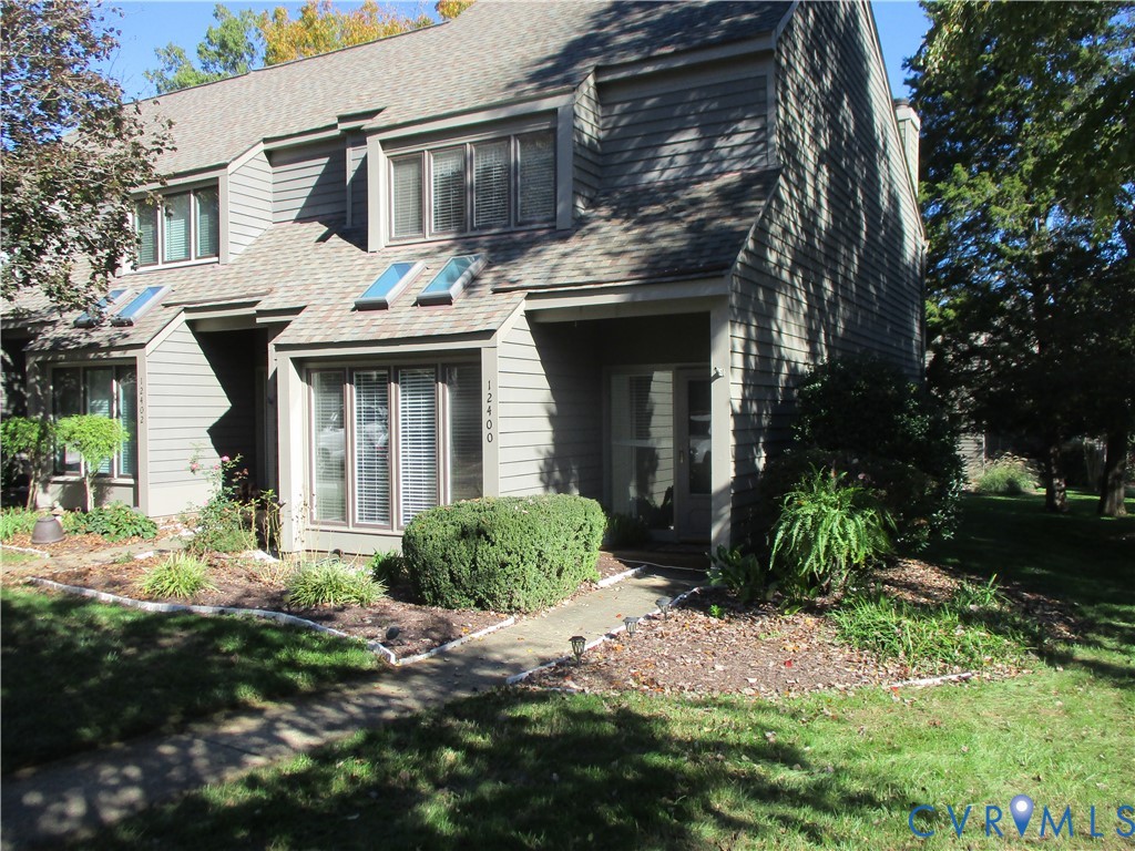 Multi-level exterior featuring horizontal lap siding, multi-pane bay windows, skylights, and a concrete walkway