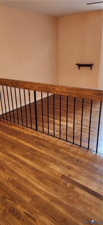 Wood-finish flooring with a natural grain texture, featuring a wooden handrail supported by vertical metal balusters and a wall-mounted display shelf