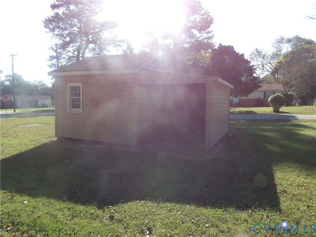Outbuilding featuring horizontal lap siding, a pitched roof, a multi-pane window, and an attached open-air storage area