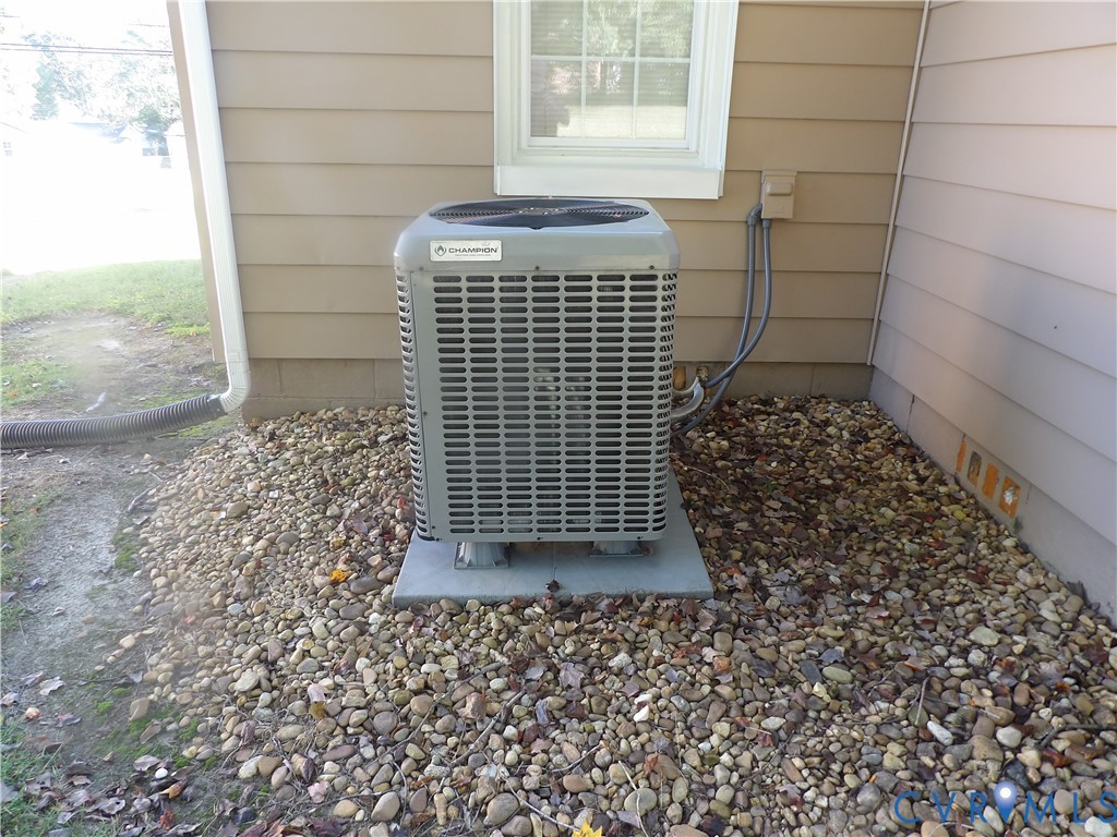 Exterior HVAC unit mounted on a concrete pad, surrounded by a stone landscape border