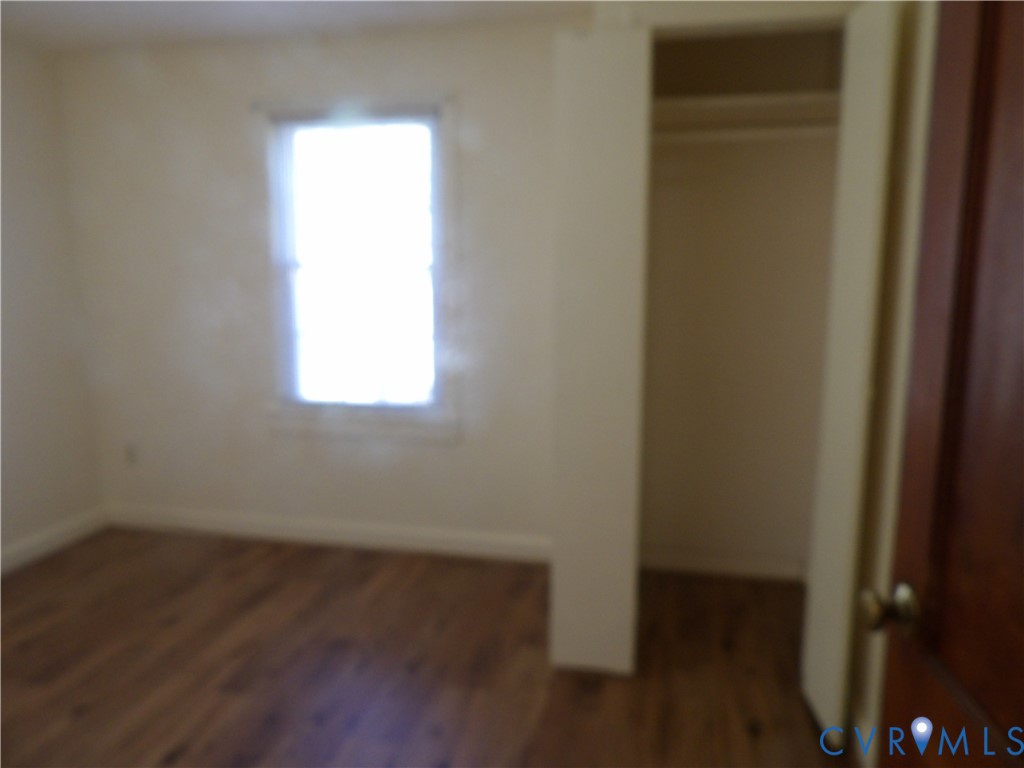 Room featuring wood-finish flooring, a single window, and a built-in closet with an interior hanging rod