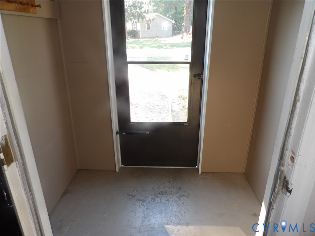 Entryway featuring a full-light glass door with black trim and a concrete floor