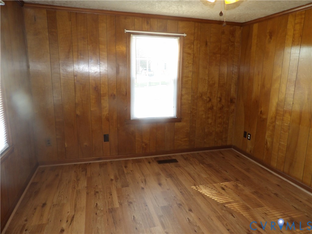 Wood-paneled interior walls, wood-finish flooring, and a central window with horizontal blinds