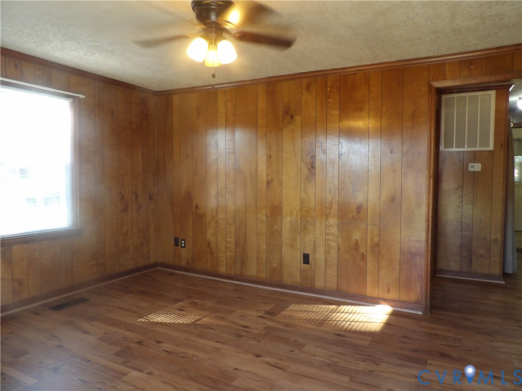 Interior space featuring wood-paneled walls, wood-finish flooring, and a ceiling-mounted light fixture with a central fan