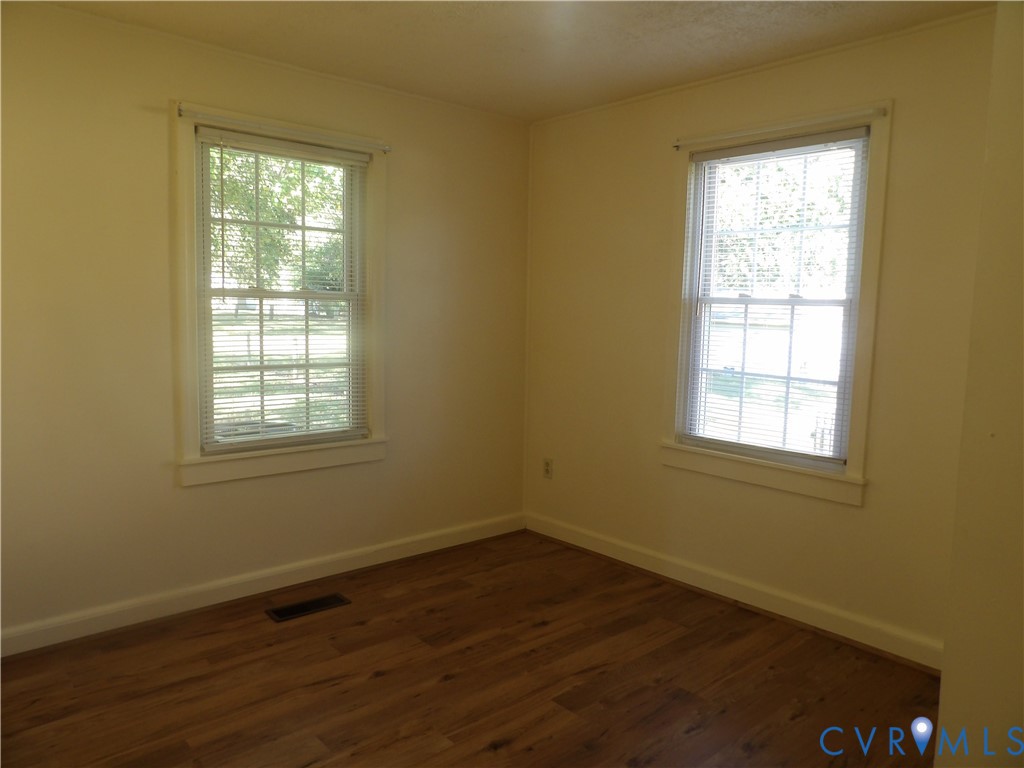 Room featuring wood-finish flooring, neutral wall paint, and two double-hung windows with exterior casing