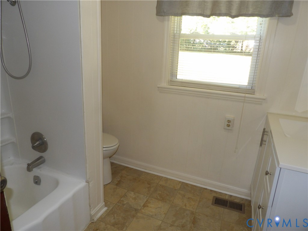 Bathroom featuring a shower-tub combination, white vanity with nickel-finish hardware, window with horizontal blinds, and tiled flooring