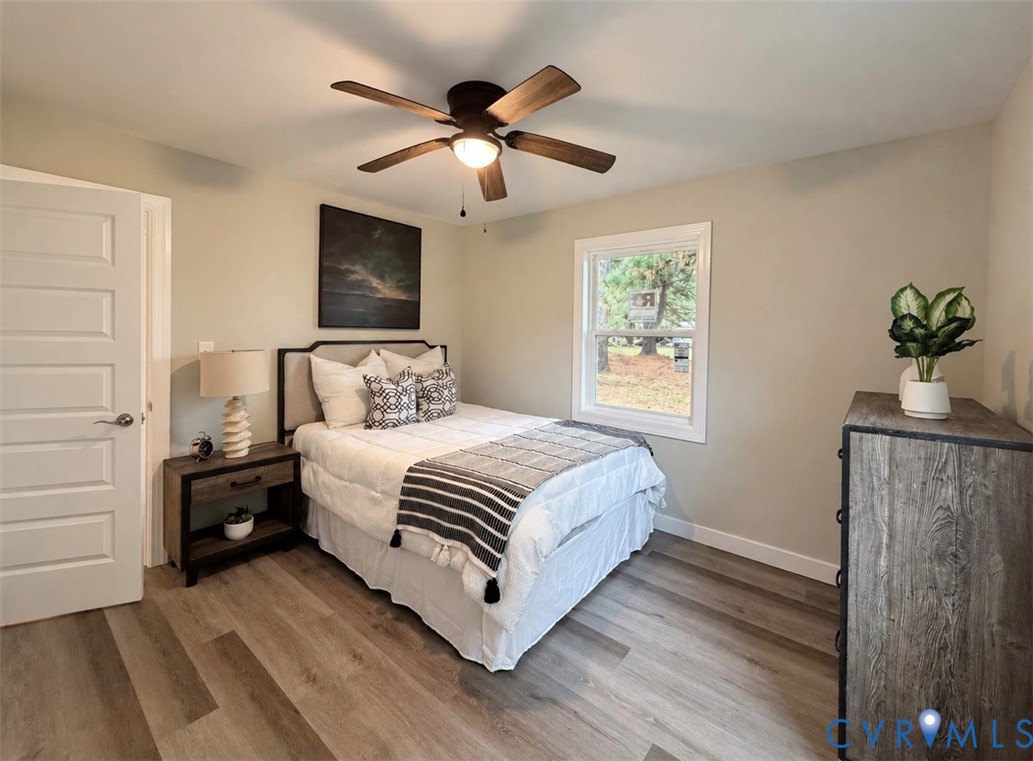 Wood-finish flooring, multi-panel interior door, and five-blade ceiling fan with integrated lighting