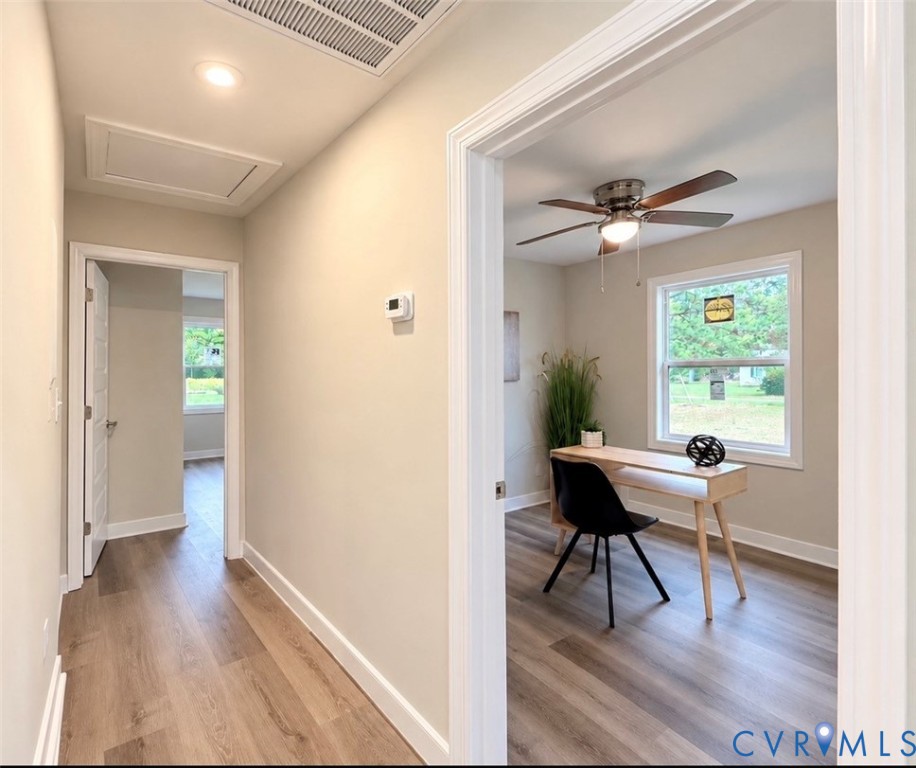 Hallway and room interior featuring wood-finish flooring, neutral wall paint, recessed lighting, and a ceiling fan with integrated light fixture