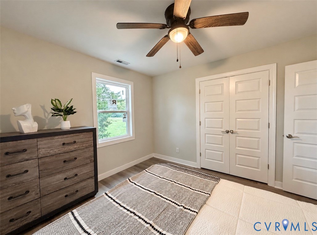 Room featuring wood-finish flooring, a ceiling fan with integrated lighting, a single window, and multi-panel interior doors