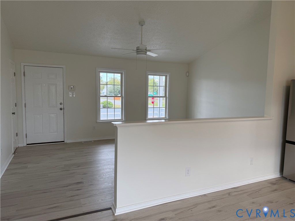 Vaulted ceilings, wood-finish flooring, dual windows, ceiling fan, and half-wall divider