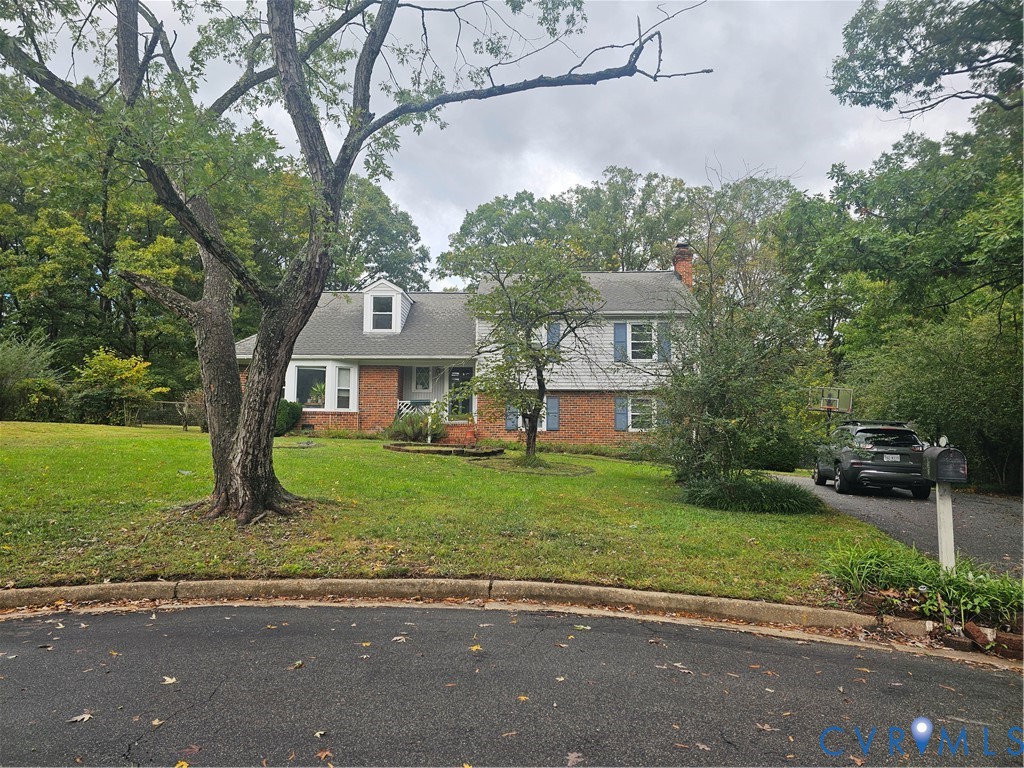 Two-story residence featuring a brick and siding exterior, front dormer window, asphalt driveway, and mature trees on a lot