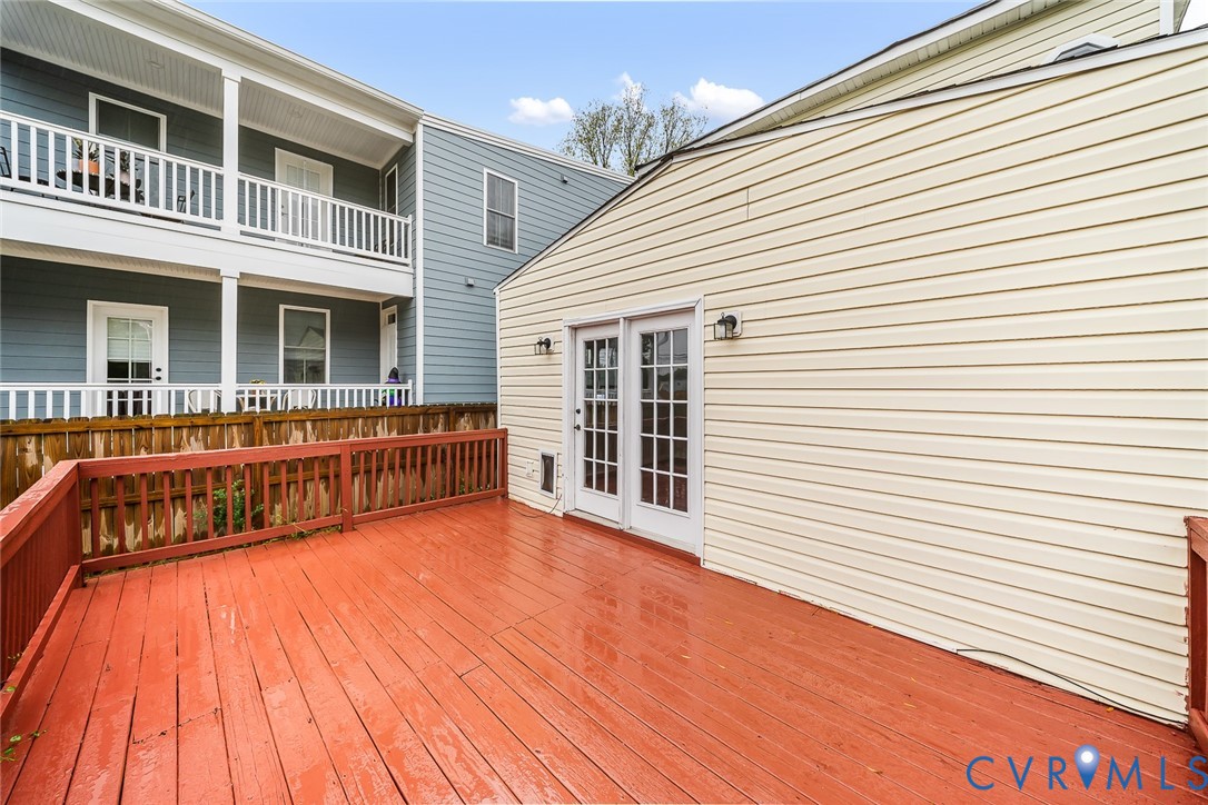 Elevated wood-plank deck featuring a perimeter railing and double-pane glass doors