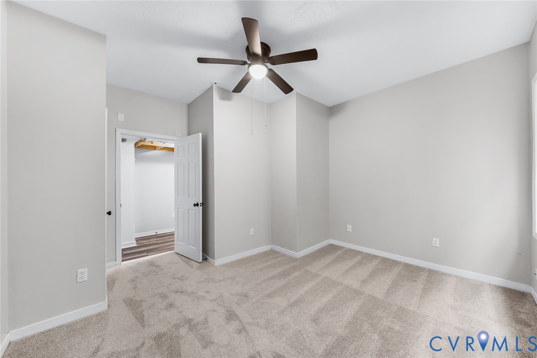 Neutral wall paint with wall-to-wall carpeting, overhead ceiling fan with integrated lighting, and six-panel interior door