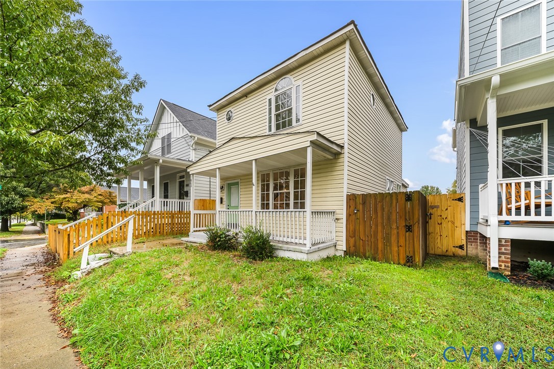 Vinyl-sided exterior featuring a covered front porch with white railing, arched window detailing, and a privacy wood fence