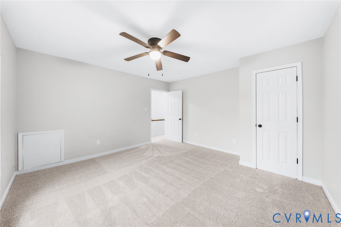 Neutral wall tones, wall-to-wall carpeting, ceiling fan with integrated lighting, and six-panel interior doors