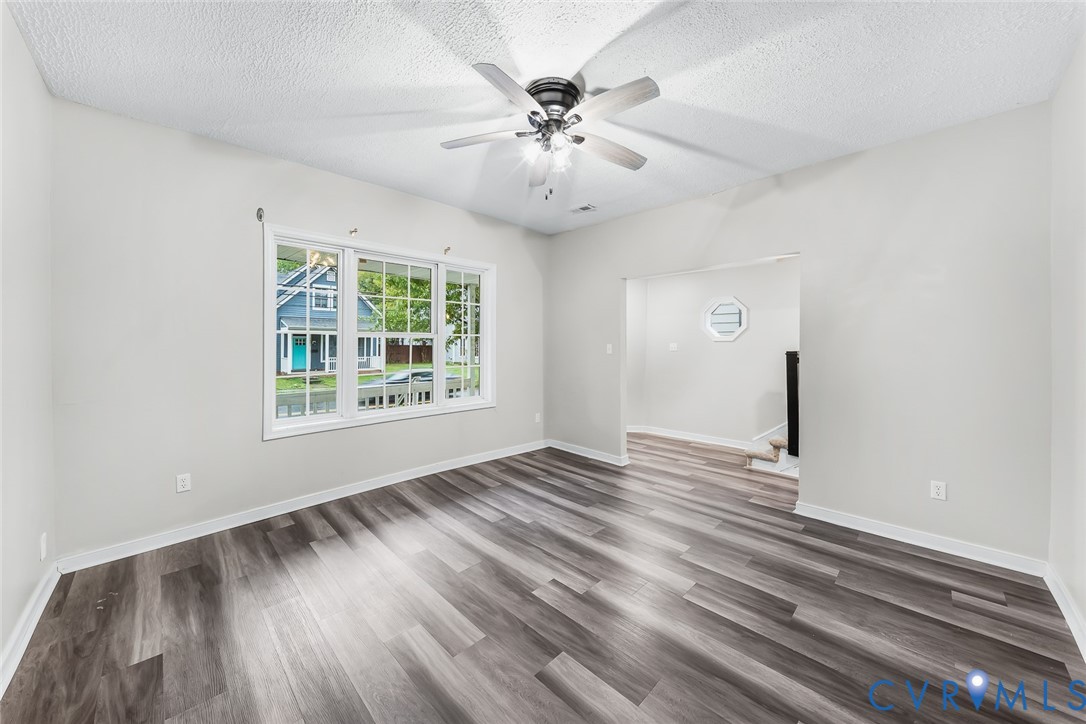 Interior space featuring wood-finish flooring, a multi-pane window, and a central ceiling fan with an integrated light fixture