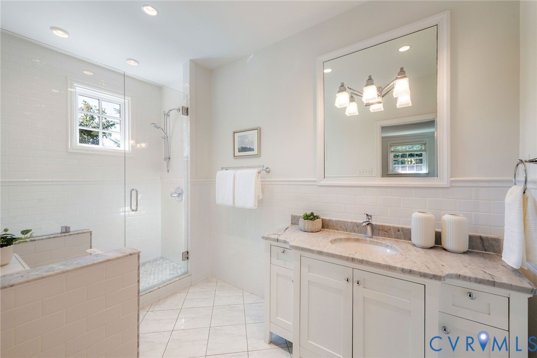 Serene marble and tile in the renovated primary bathroom.