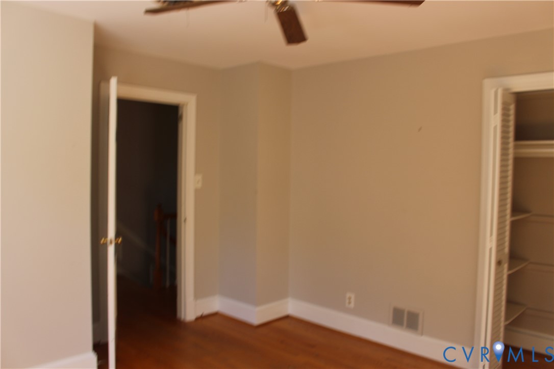 Interior room featuring wood-finish flooring, neutral wall paint, and a ceiling fan with integrated light fixture