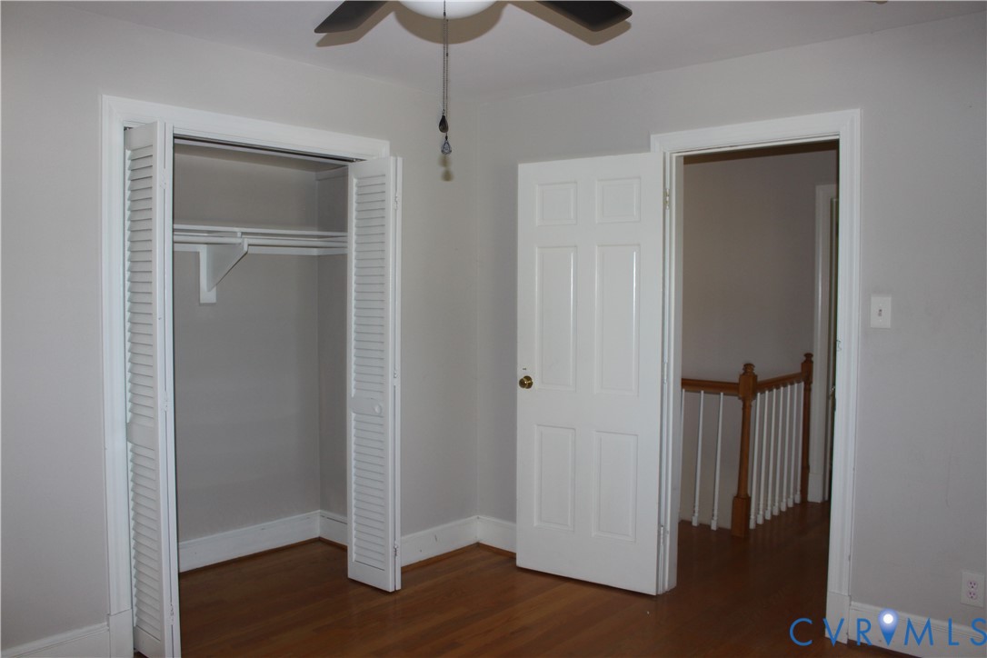 Room featuring wood-finish flooring, a closet with louvered doors, and a ceiling fan with integrated lighting