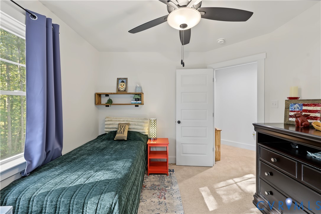 Neutral-toned room featuring a central ceiling fan with an integrated light fixture, wall-to-wall carpeting, and a five-panel interior door