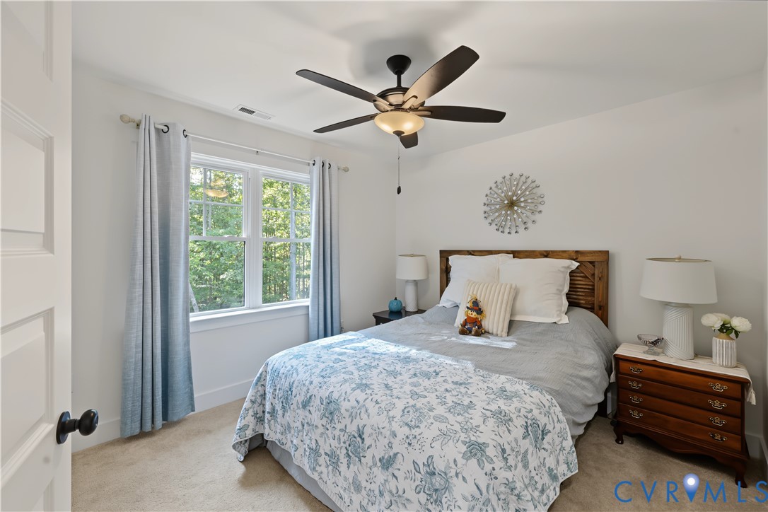Bedroom featuring a ceiling fan with integrated lighting, a double-hung window, and neutral carpeting
