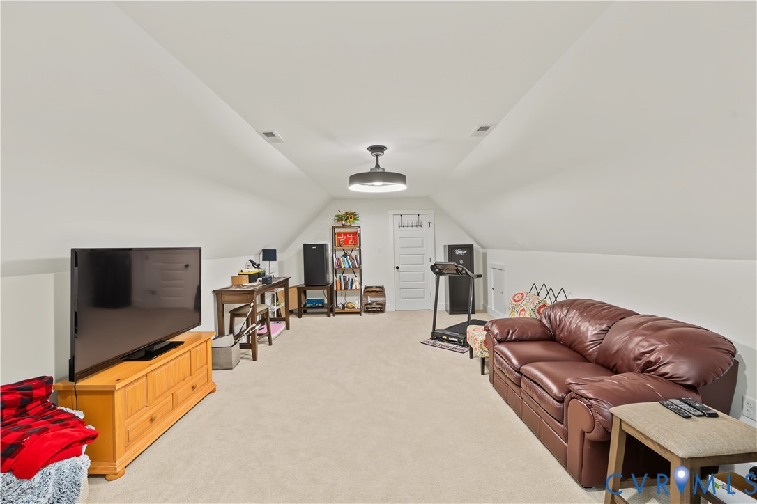 Vaulted ceilings with recessed lighting, neutral carpeting, and a multi-panel door