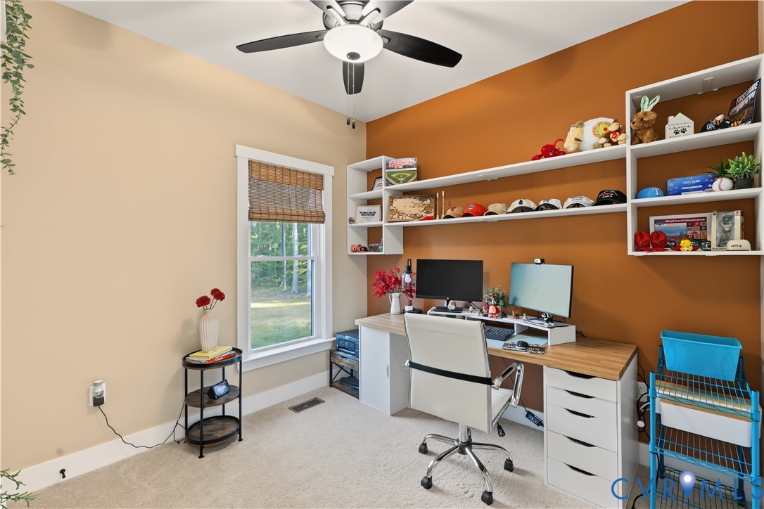 Built-in white shelving, integrated desk surface with drawer storage, ceiling fan with light fixture, and window with woven shade