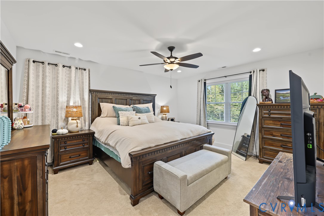 Neutral-toned wall-to-wall carpeting, recessed ceiling lighting, and a multi-blade ceiling fan with a centered light fixture