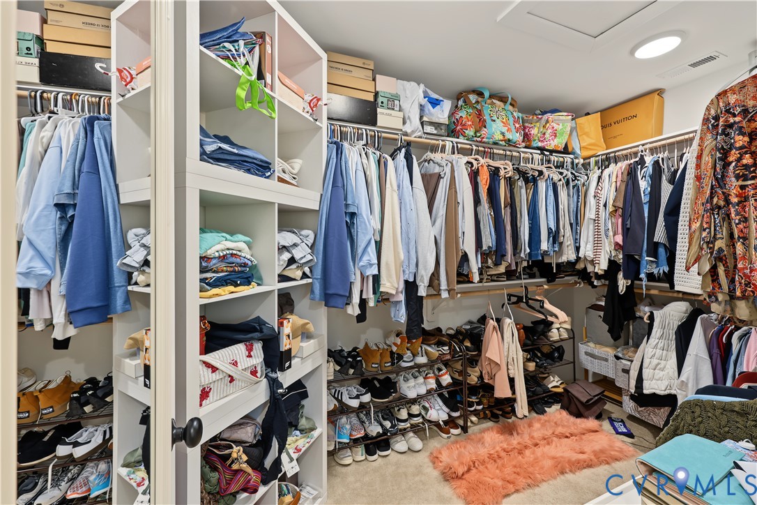 Walk-in closet featuring built-in white shelving towers and integrated hanging garment rods