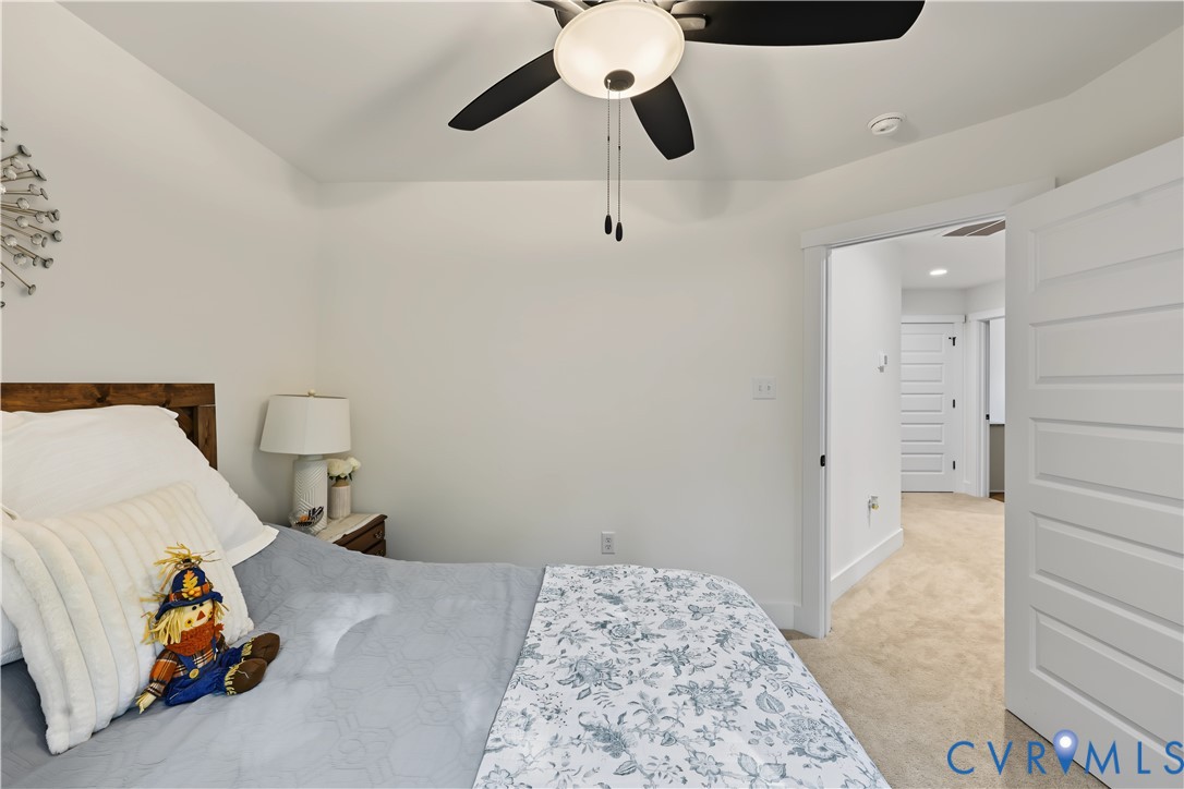 Neutral-toned room featuring a vaulted ceiling, ceiling fan with integrated lighting, and white five-panel interior doors