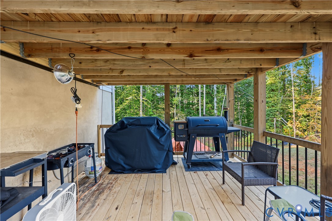 Covered wood deck featuring exposed beam ceiling and black metal railing