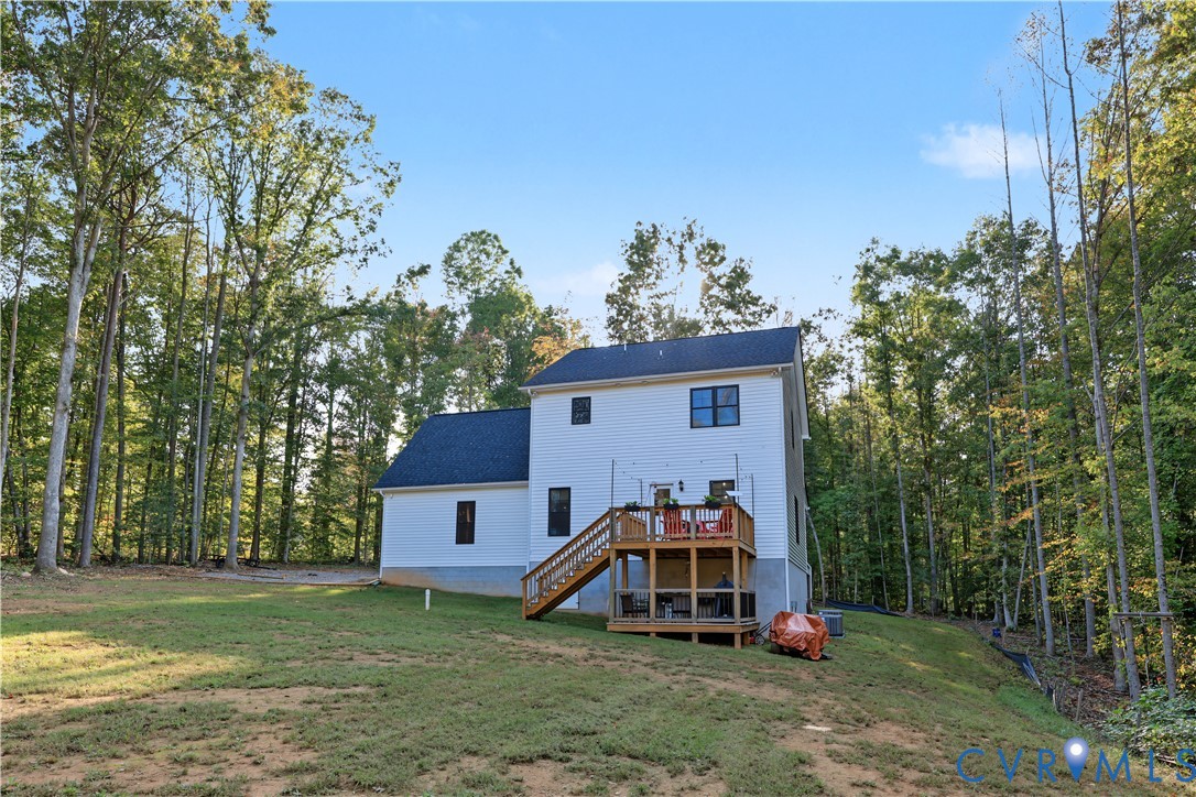 Two-story exterior with white siding, dark shingle roof, multi-level wood deck, and expansive wooded lot