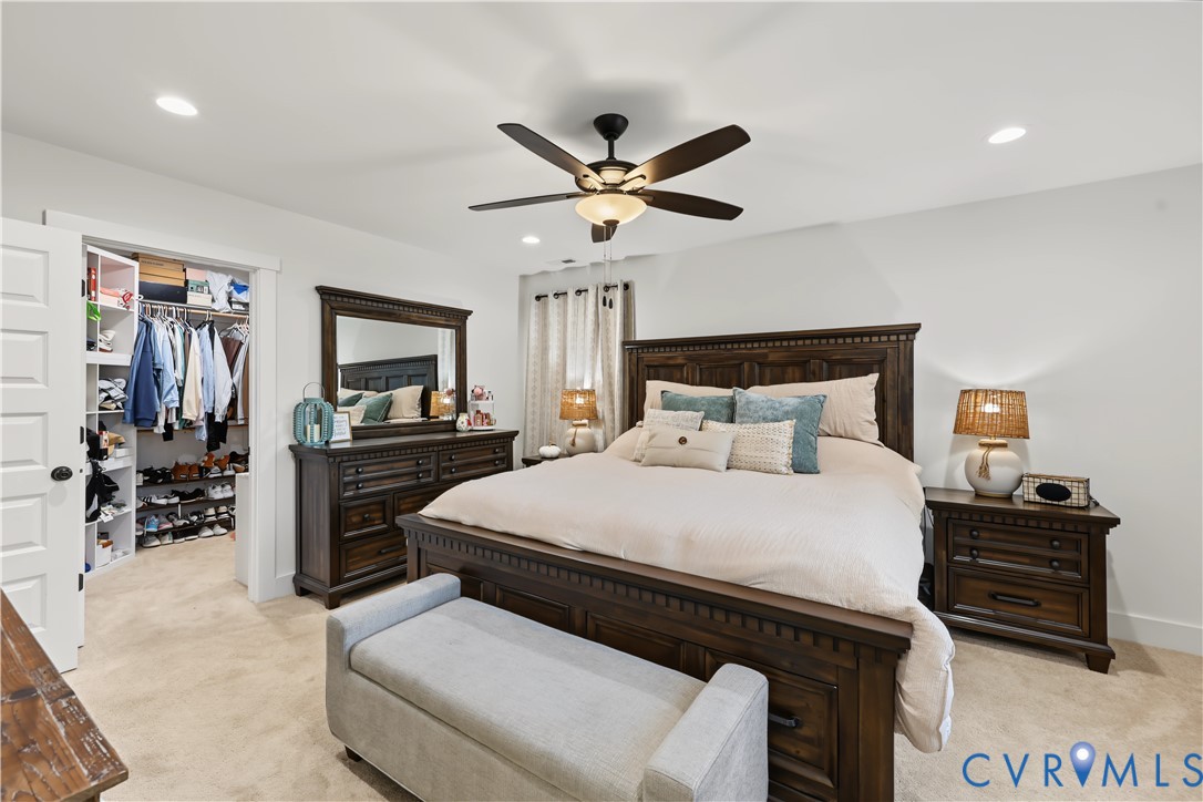 Bedroom featuring neutral wall paint, recessed lighting, carpet flooring, a central ceiling fan with integrated lighting, and a walk-in closet with built-in shelving