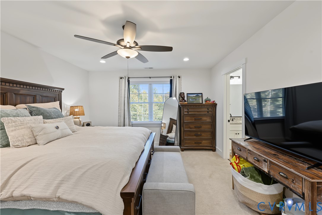 Bedroom featuring neutral carpeting, a multi-blade ceiling fan with integrated lighting, recessed lighting, and a doorway leading to a secondary room
