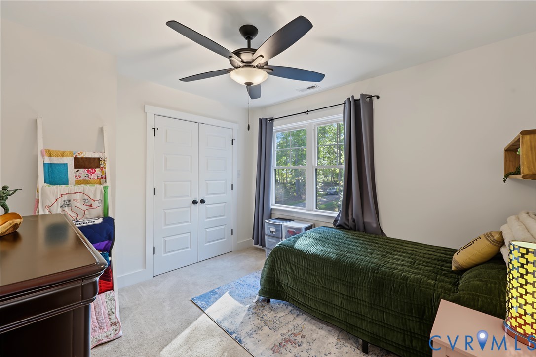Bedroom featuring neutral wall paint, carpeted flooring, a ceiling fan with integrated lighting, a double-door closet, and a multi-pane window