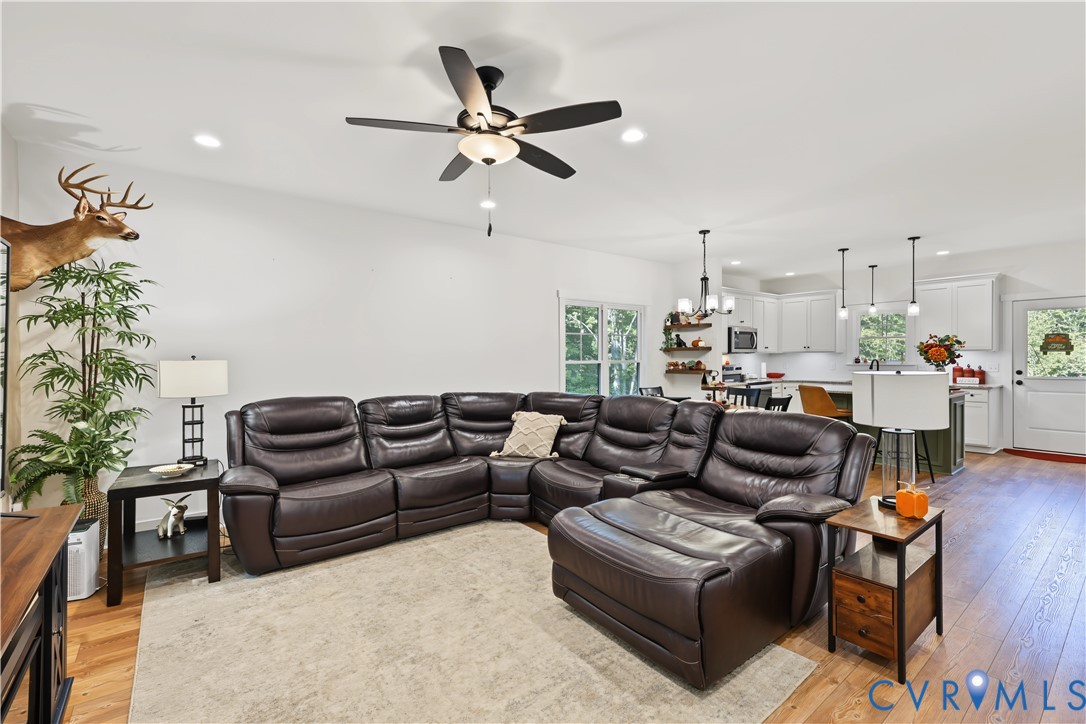 Open-concept interior featuring wood-finish flooring, recessed lighting, and a five-blade ceiling fan