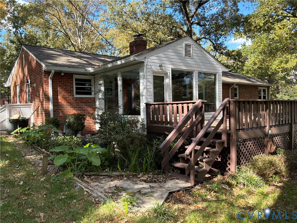 Exterior featuring red brick masonry, white wood siding, a brick chimney, and a multi-level wood deck with lattice skirting