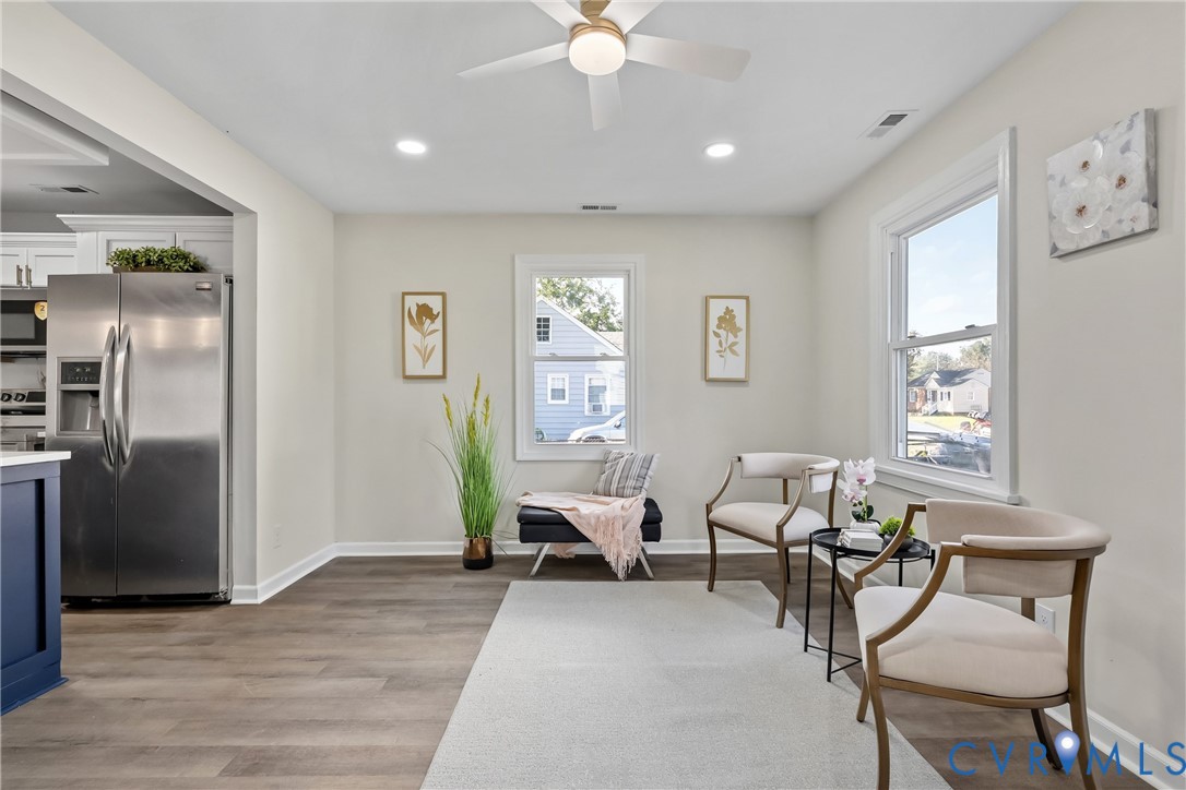 Neutral-toned interior featuring wood-finish flooring, recessed lighting, a modern ceiling fan, and large windows with white trim Neutral-toned interior featuring wood-finish flooring, recessed lighting, a modern ceiling fan, and large windows with white trim