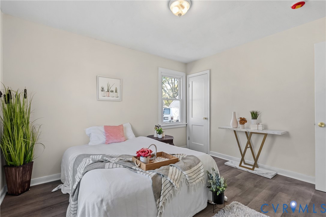 Neutral-toned interior featuring wood-finish flooring, a double-hung window, and a single-panel interior door with satin-finish hardware