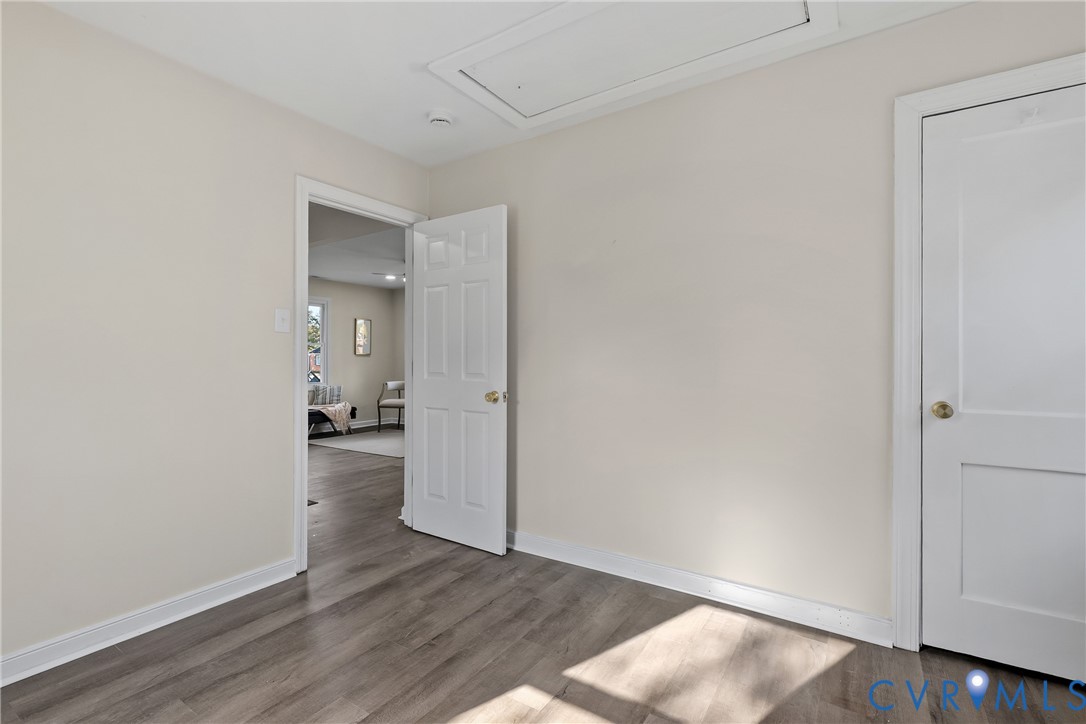 Interior space featuring wood-finish flooring, two-panel interior doors with metallic hardware, and an attic access panel