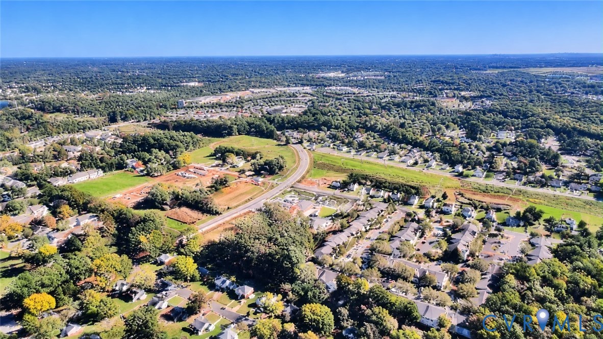 Aerial perspective showcasing expansive suburban landscape, abundant mature canopy cover, extensive green space, and established road infrastructure