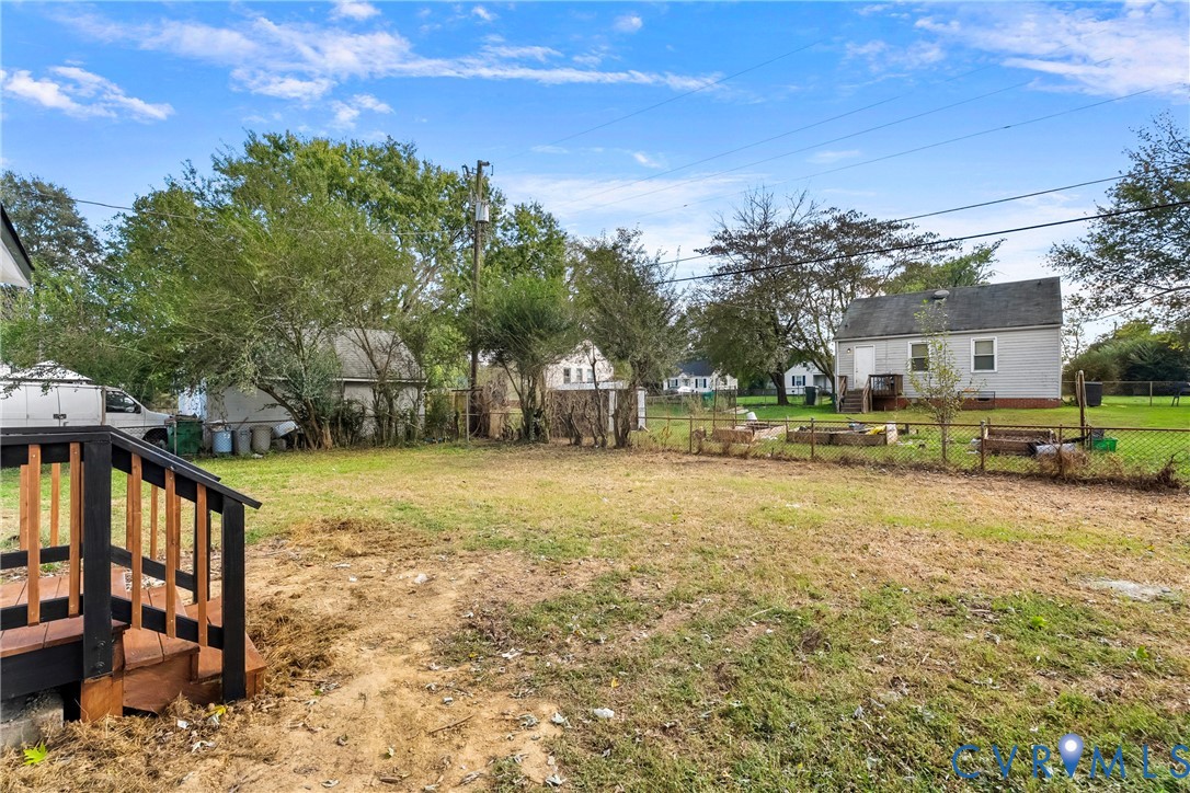 Spacious backyard featuring wood-frame decking, chain-link perimeter fencing, and mature trees