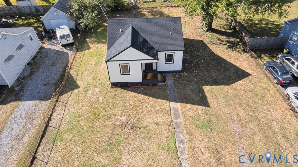 Single-story residence featuring a gable roof, exterior siding with contrast trim, a front-entry porch, and a detached structure located on a lot with a gravel driveway
