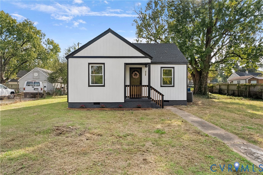 Single-story residence featuring white board-and-batten siding with dark trim, an asphalt shingle roof, a covered front porch with railing, and a concrete walkway Single-story residence featuring white board-and-batten siding with dark trim, an asphalt shingle roof, a covered front porch with railing, and a concrete walkway
