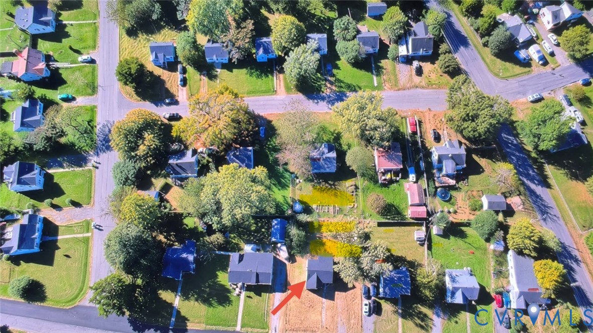 Aerial perspective of a residential lot featuring mature trees, established landscaping, and a rectangular property footprint