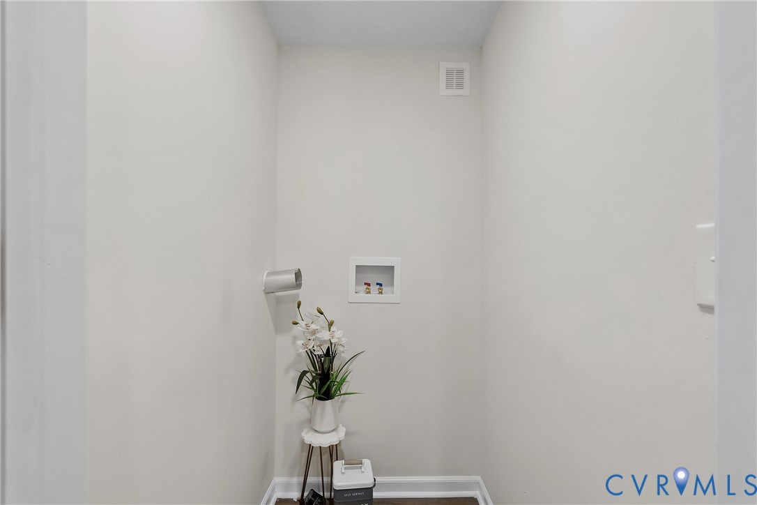 Dedicated laundry area featuring a wall-mounted dryer vent and a recessed water supply box