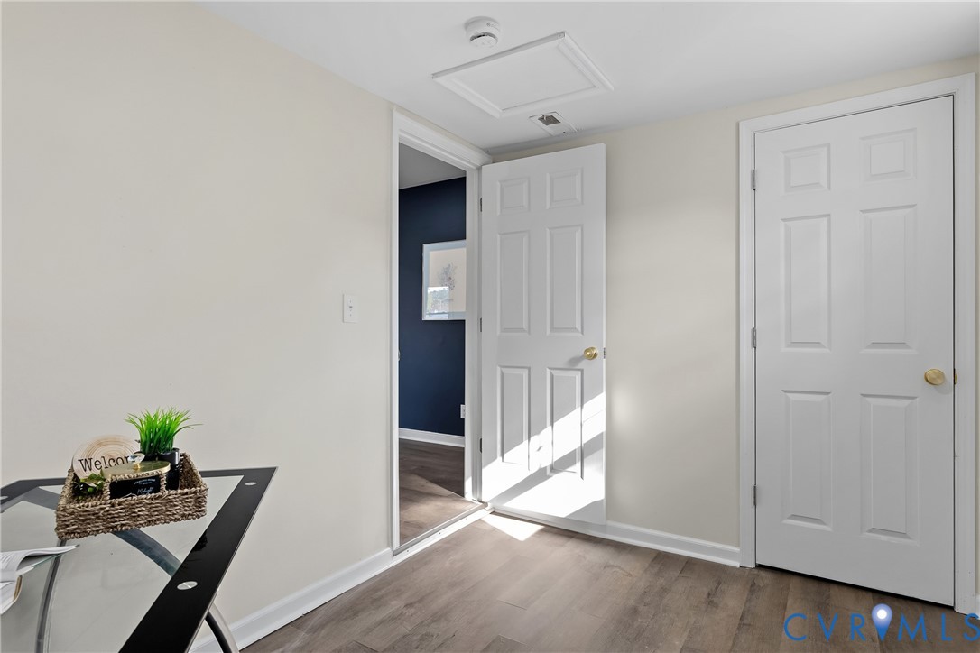 Wood-finish flooring, white six-panel doors with brass-tone hardware, and ceiling access panel